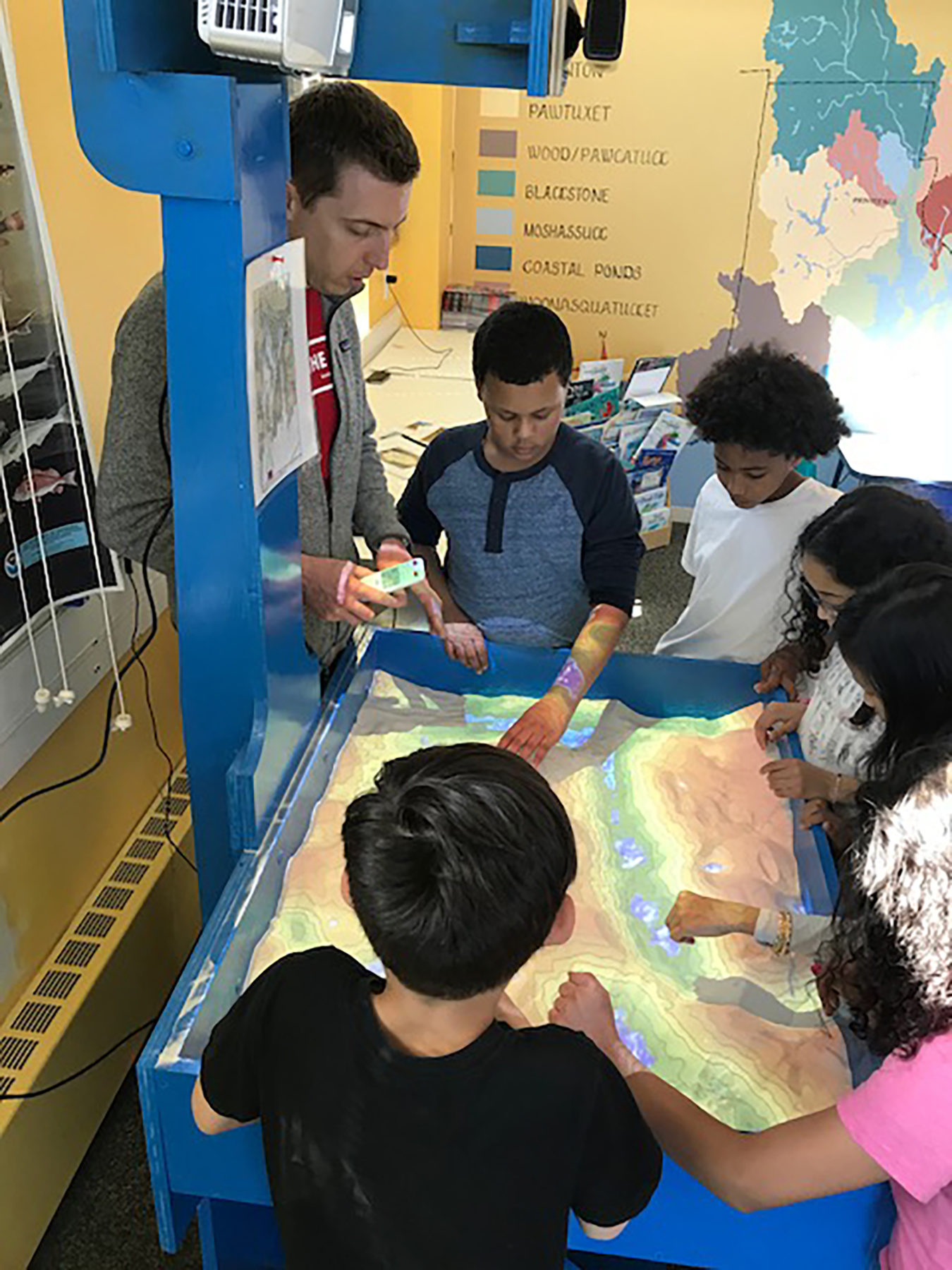 Educator Chris Dodge demonstrates watershed using the augmented reality sandbox